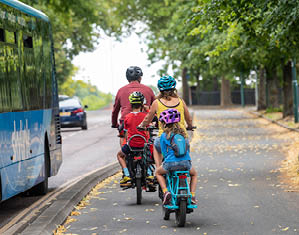 Family cycling in cycle lane near bus