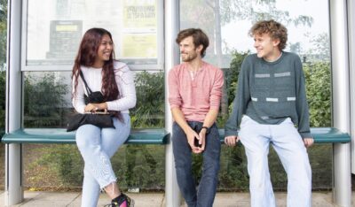 Three people sitting at Wilford Lane tram stop